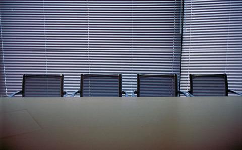 Kuva tyhjästä neuvottelupöydästä ja tuoleista hämärässä huoneessa. Kuvan lähde: Pixhill.